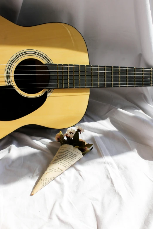 a wooden guitar sitting on a white sheet with a fake animal's foot resting on it