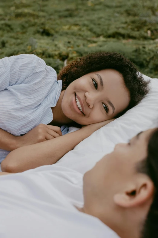 a smiling woman lies on the bed next to another girl