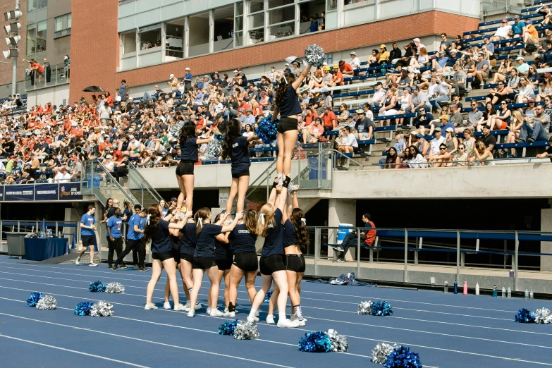 cheerleaders standing on the sideline cheering at an event