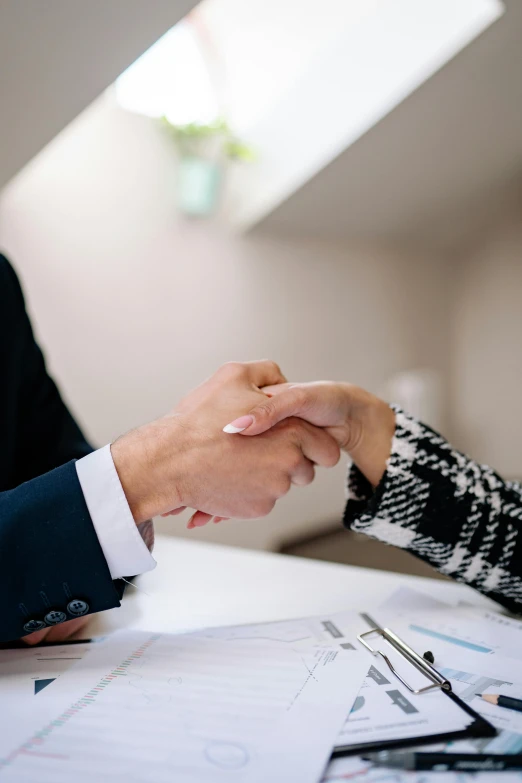 a close up of two people shaking hands over some papers