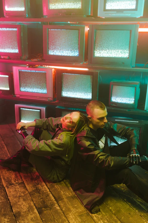 the couple is sitting down in front of tv screens