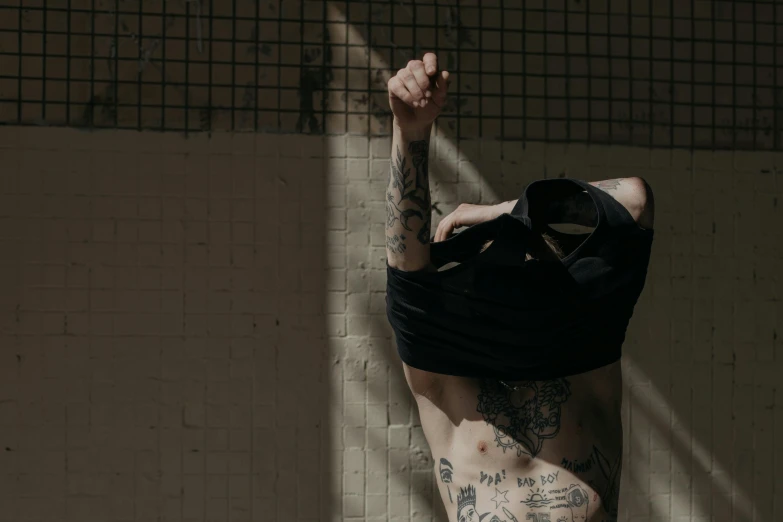 a tattooed man is leaning against a wall in a room