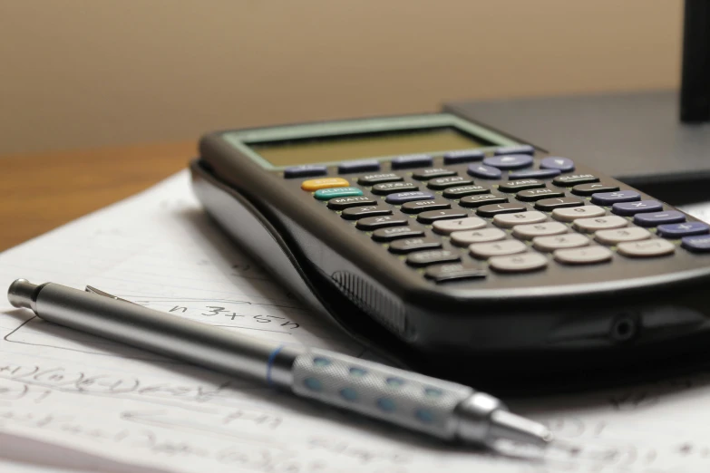 a calculator next to a pen on top of a desk