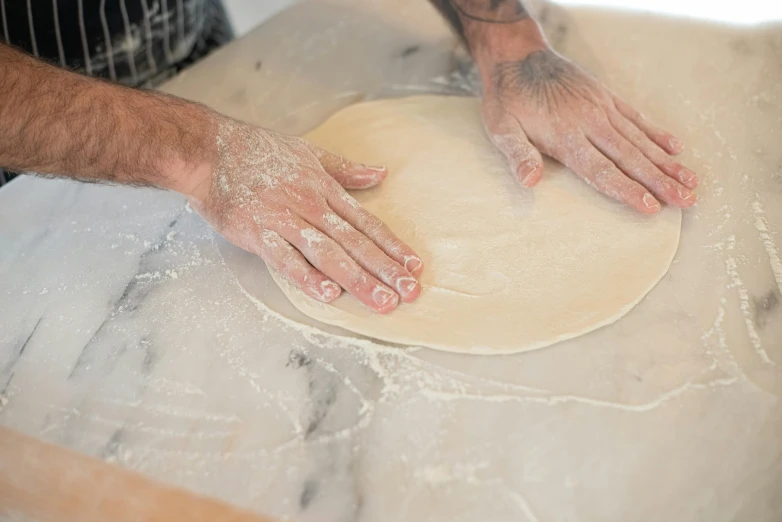 hands roll the dough onto floured surface