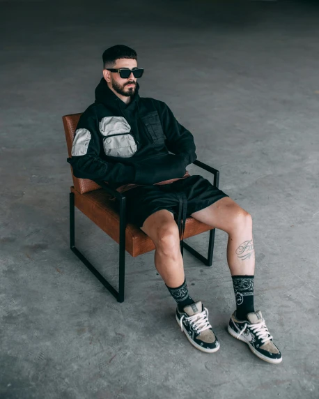 a man is sitting on a chair wearing all black