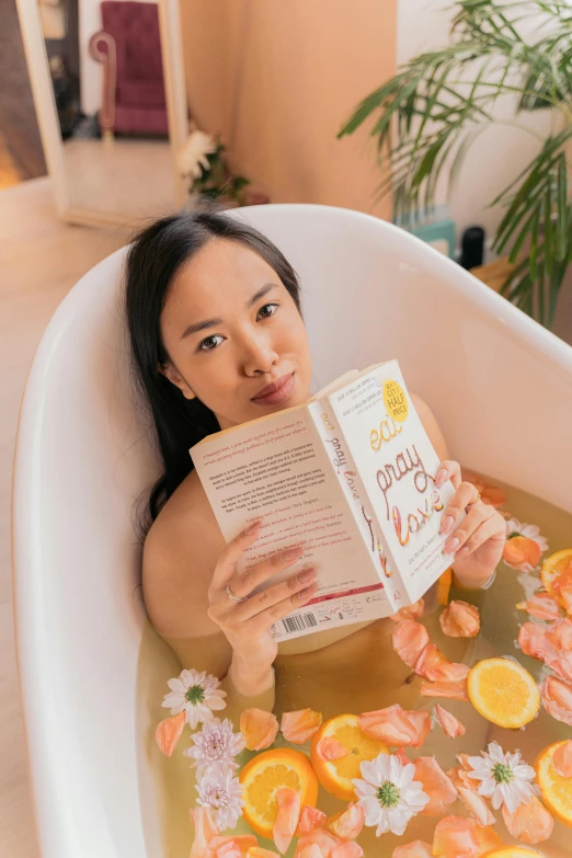 an attractive woman in a bathtub reading a book