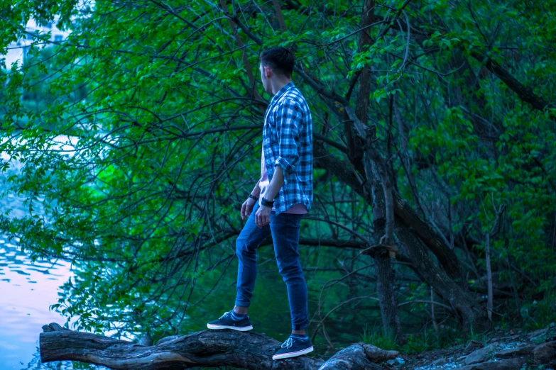 a man standing on a log next to a lake