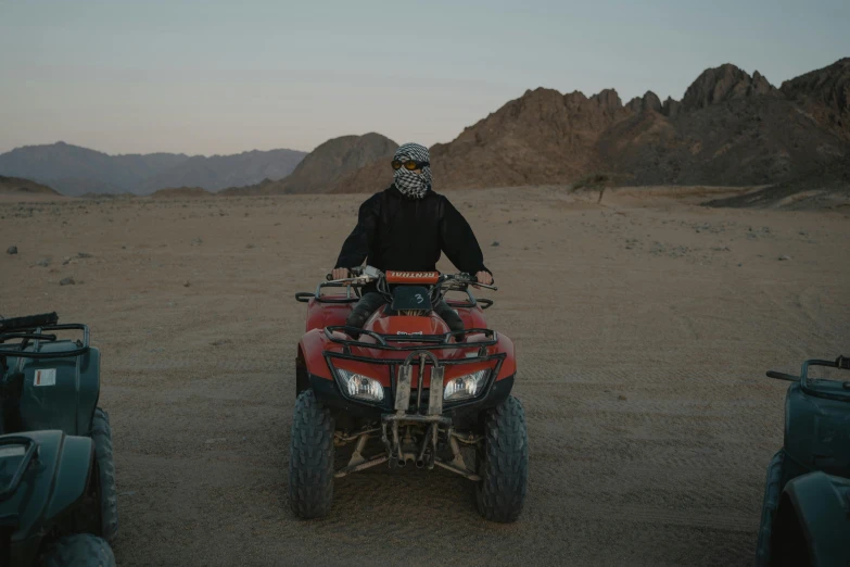 a man on an atv rides through a desert area