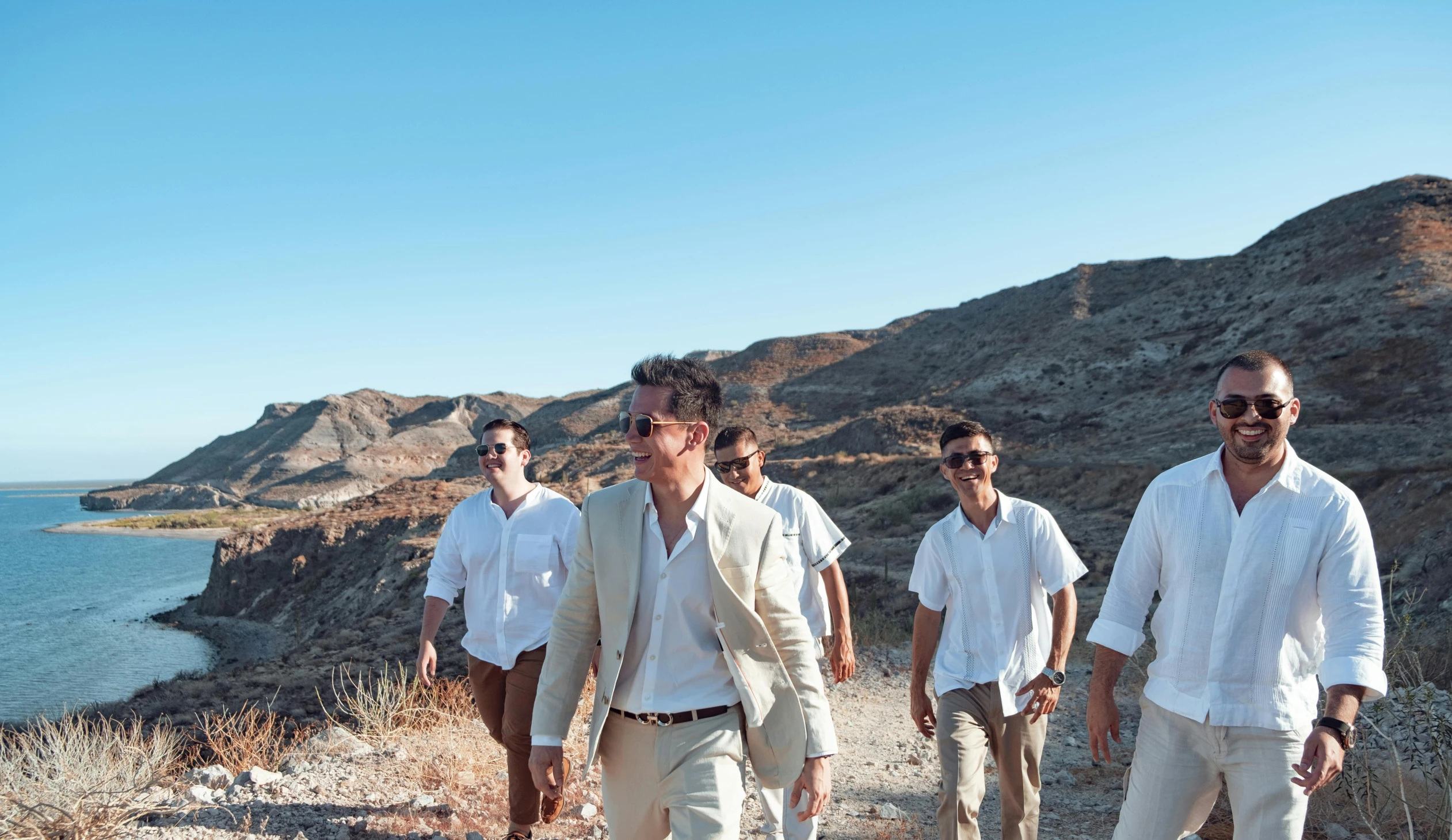 a group of men walking up a hill near the ocean