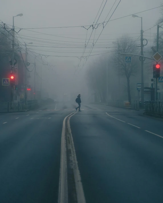 person walking on an empty street in the middle of the rain