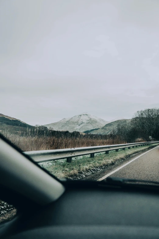 a car drives along the road towards a mountain