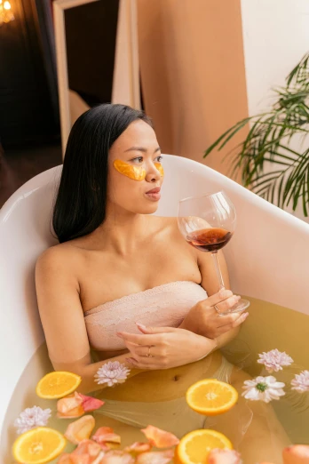 a woman with orange slices on her cheek and a face mask in a bathtub