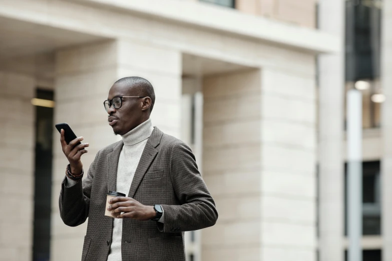 a man looking down at his phone while standing in front of a building