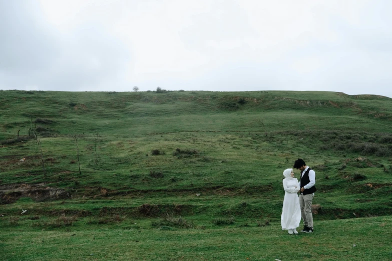 a man and woman in wedding dress standing on a hill