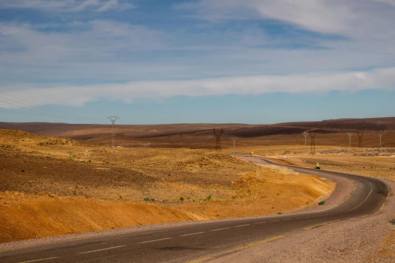 an empty dirt road leading to a distant mountain