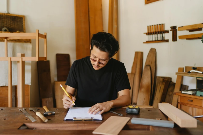 a man sitting at a table with a notebook and pencil in his hand