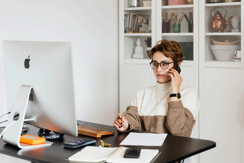 a woman sits in front of a computer with her hands to her face