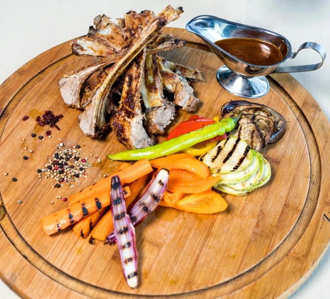 a wooden platter holds meat, veggies, and seasonings