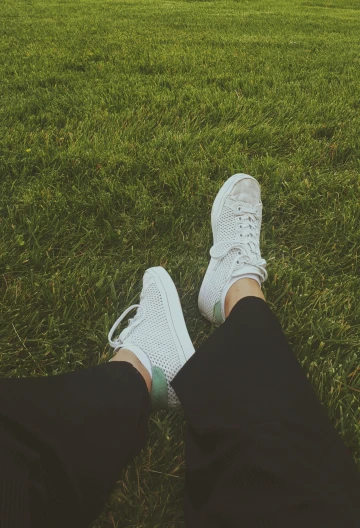 a person in sneakers laying down on the grass