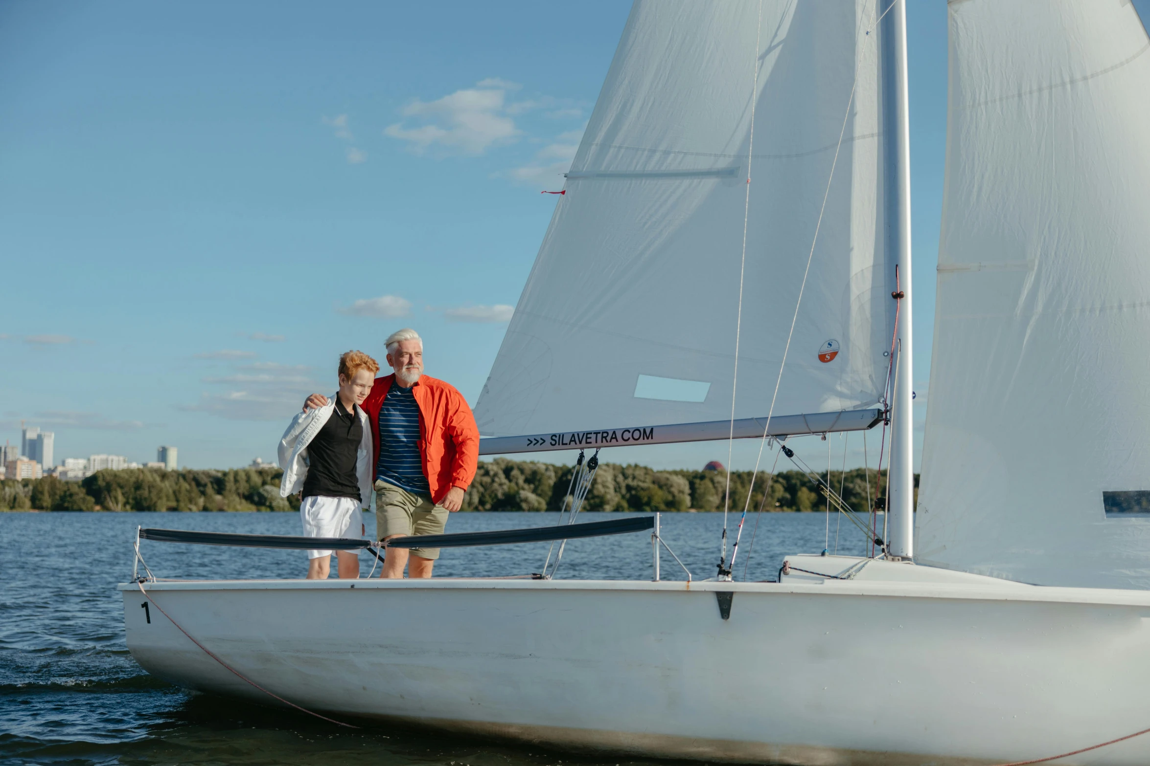 two people standing on the edge of a small sailboat