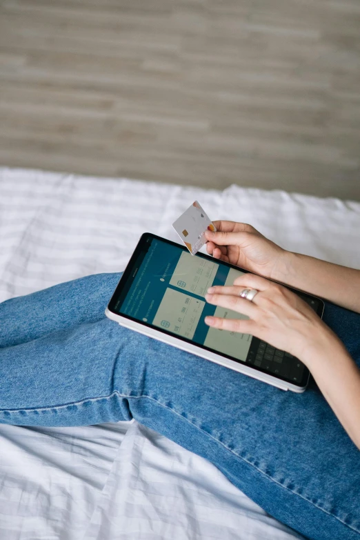 a woman sitting on her bed holding an electronic device