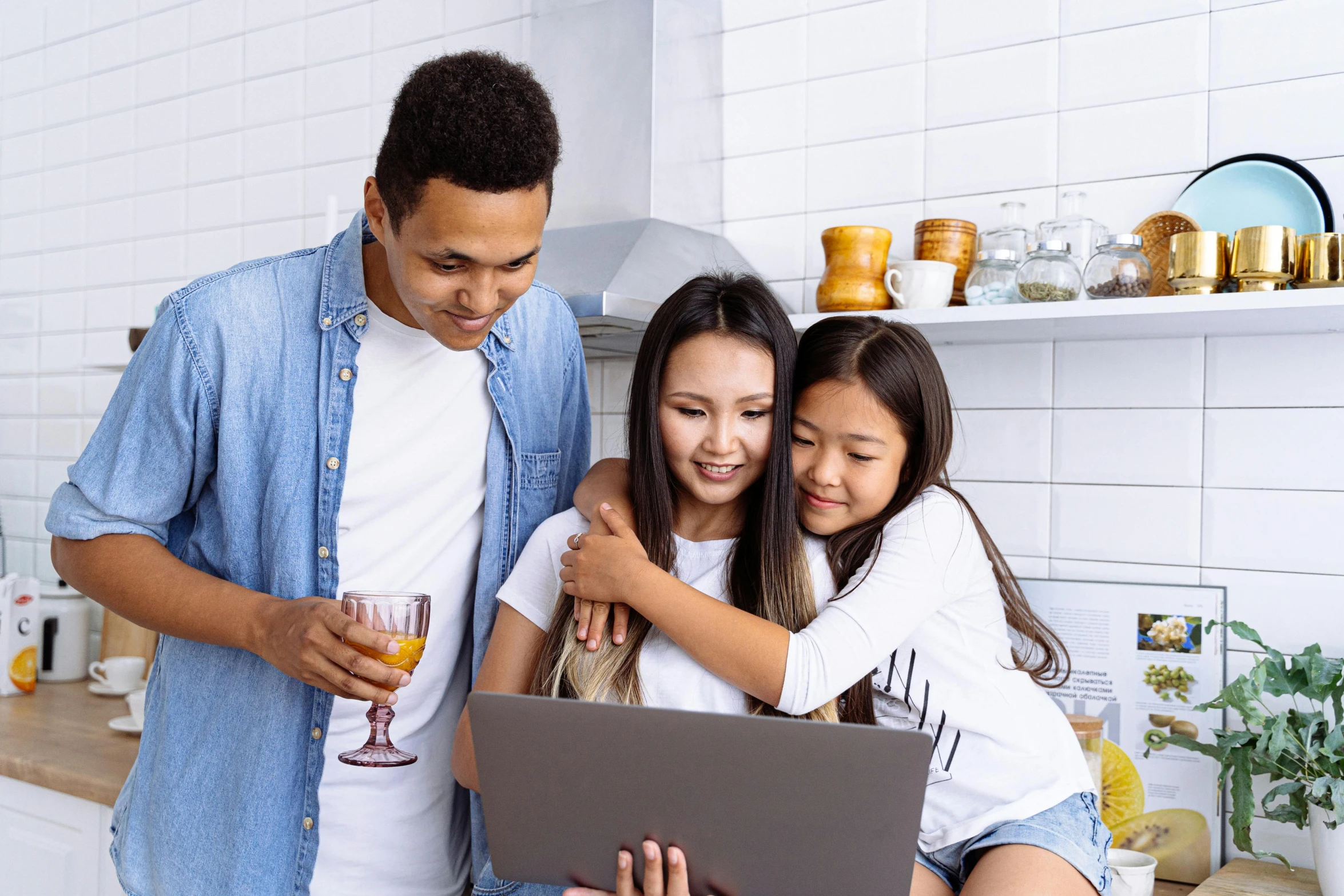 a man and two young women standing next to each other holding a laptop