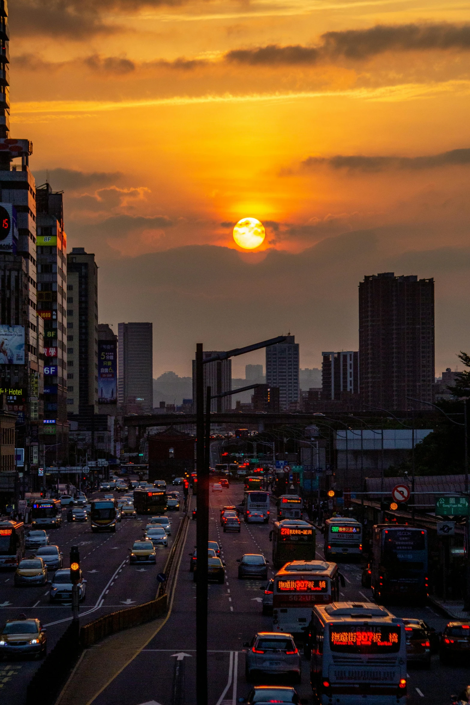 a sunset in the middle of a city filled with traffic