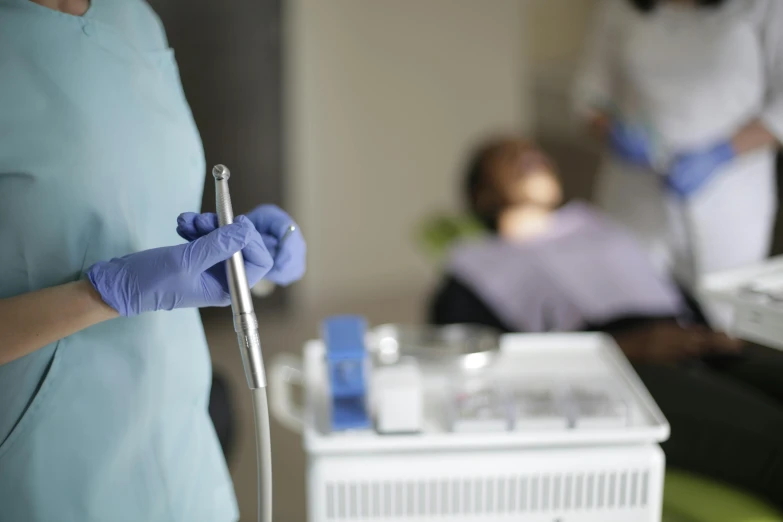 a doctor holding a blue needle preparing to perform 