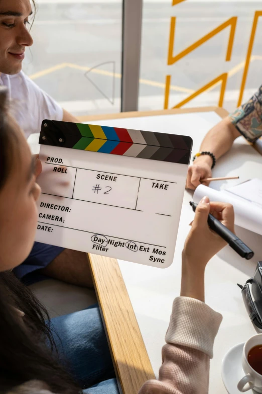 a couple sit around at a table and watch tv being filmed