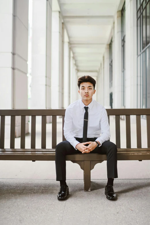 a man in a black tie is sitting on a bench