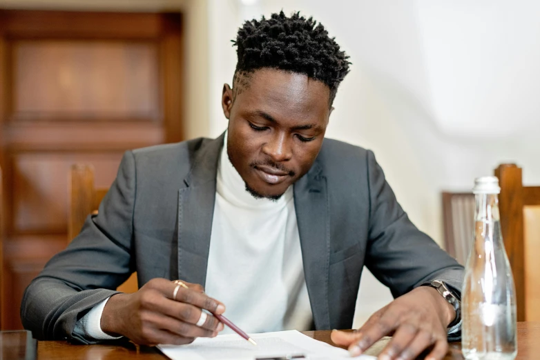 a man sitting at a wooden table signing papers