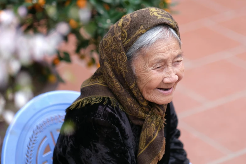 an elderly woman with a scarf is sitting on a bench
