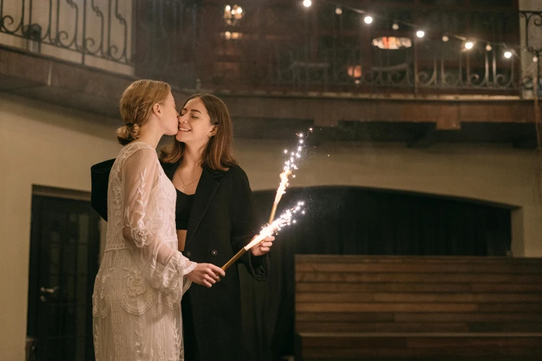 two women are standing side by side holding sparklers