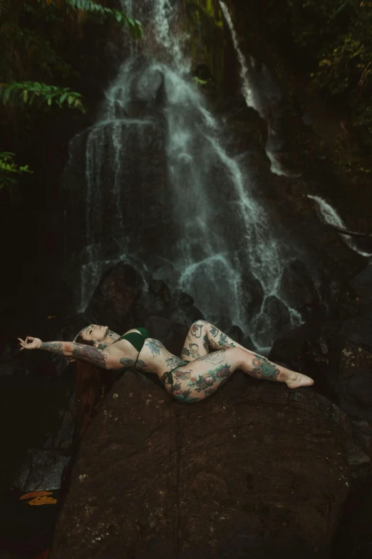 a  model is posing in front of a waterfall