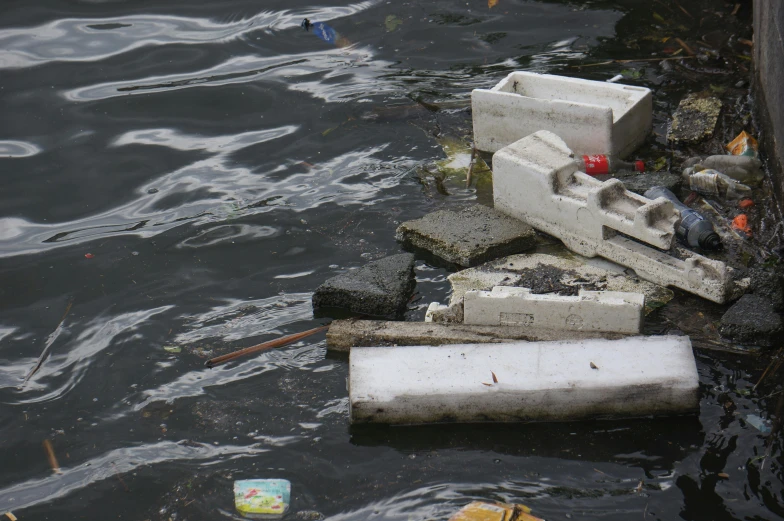 debris sits on the water near a wall