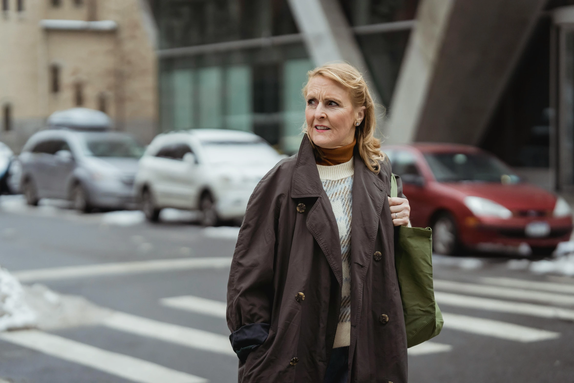 a woman holding a purse and posing for a po in front of cars