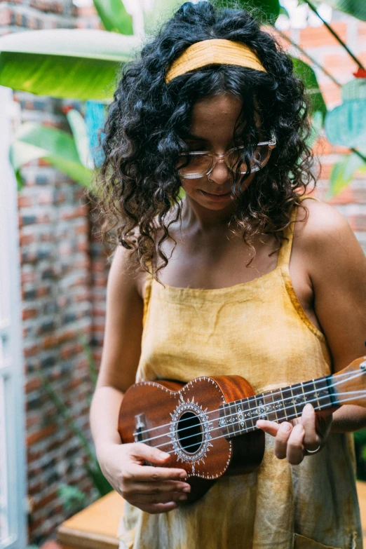 a girl playing an instrument in front of a plant