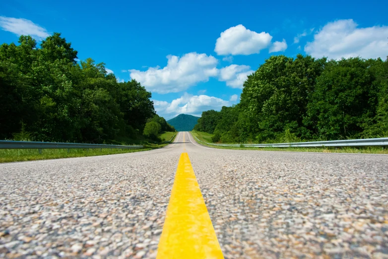 the view from the front seat of an open road, near green trees