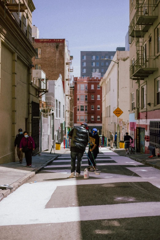 several people crossing the street with the crosswalk painted white