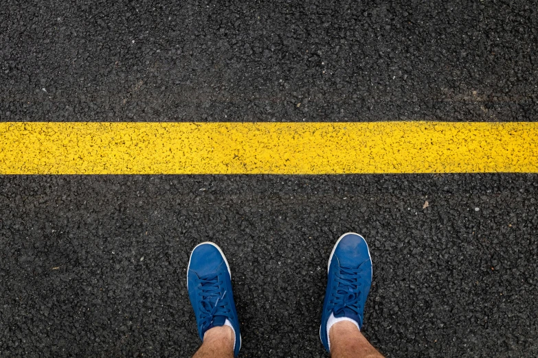 a person standing next to a yellow line on asphalt