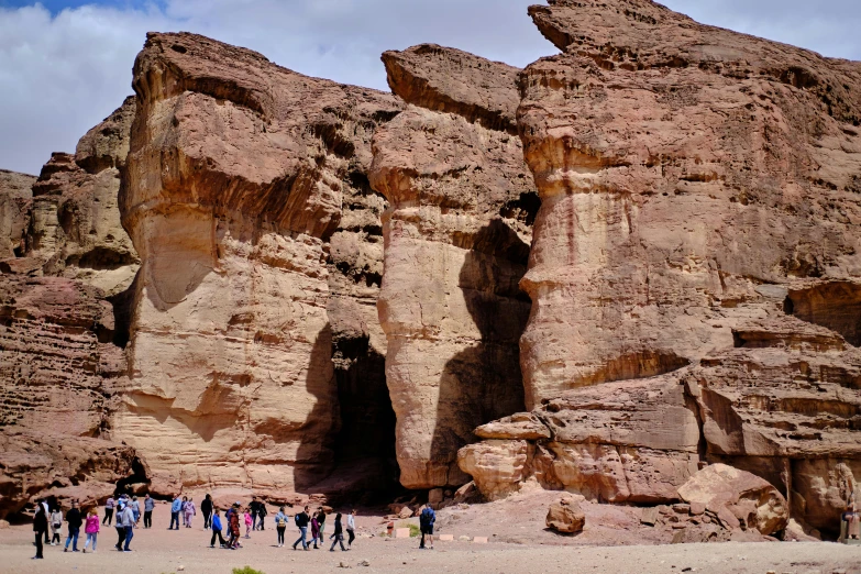 a group of people standing on top of a beach near rocks