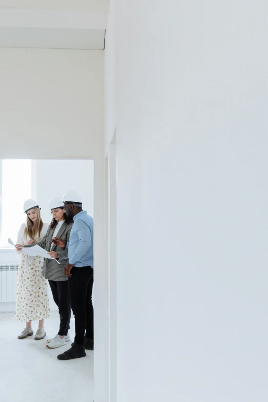 three women and two men standing with plans while looking at each other