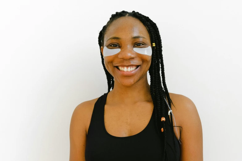 a young woman wearing eye patches stands in front of a wall