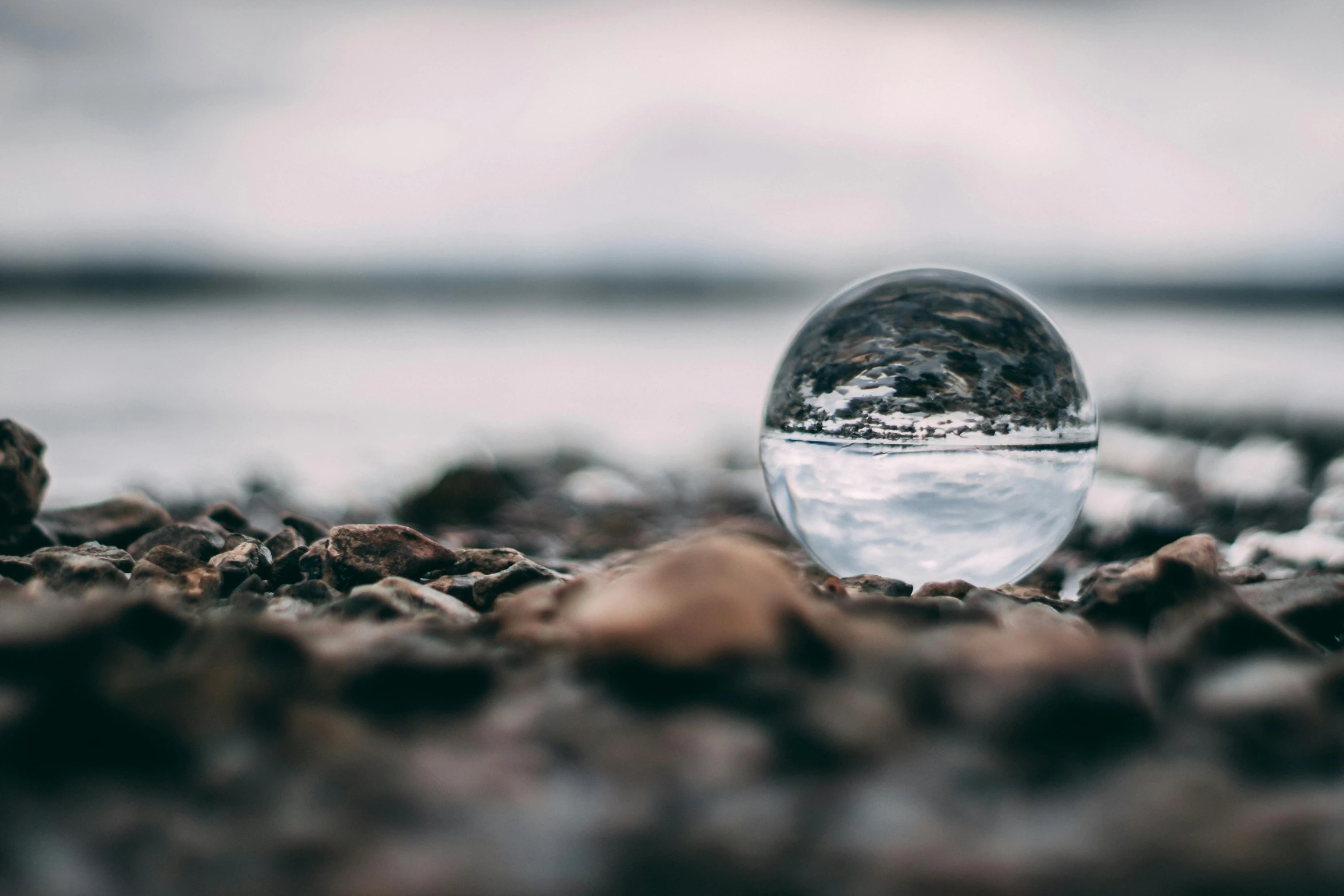 glass ball laying on the ground surrounded by rocks