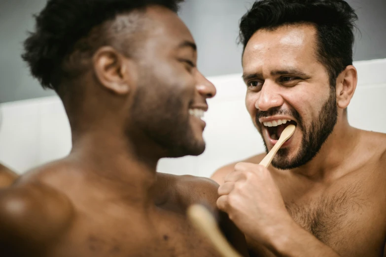 two males laughing and brushing their teeth in the bathroom