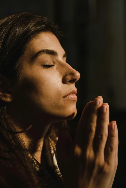 a woman with her eyes closed and her hands clasped together