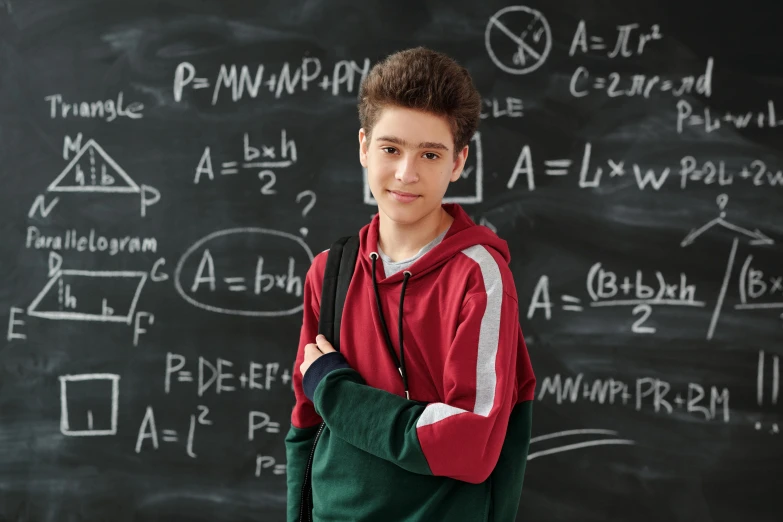 a boy standing in front of a chalkboard with chalk drawings on it
