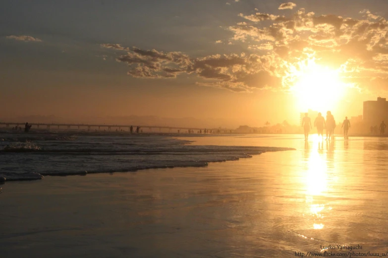 people are walking in the distance along a beach