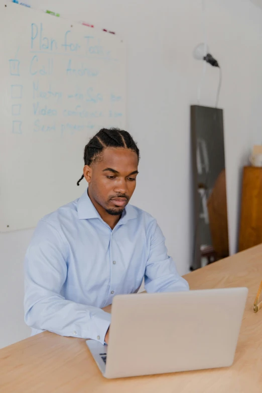 a young man is sitting at the table using a laptop computer