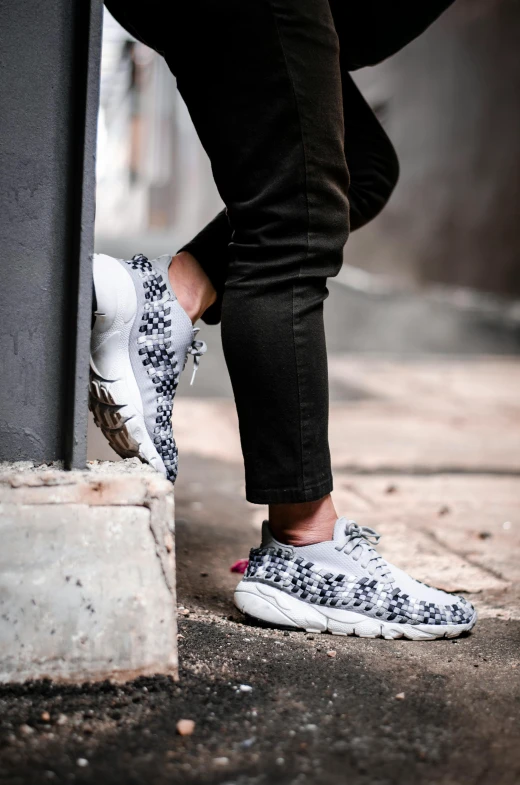 a person is wearing white sneakers that are black and white